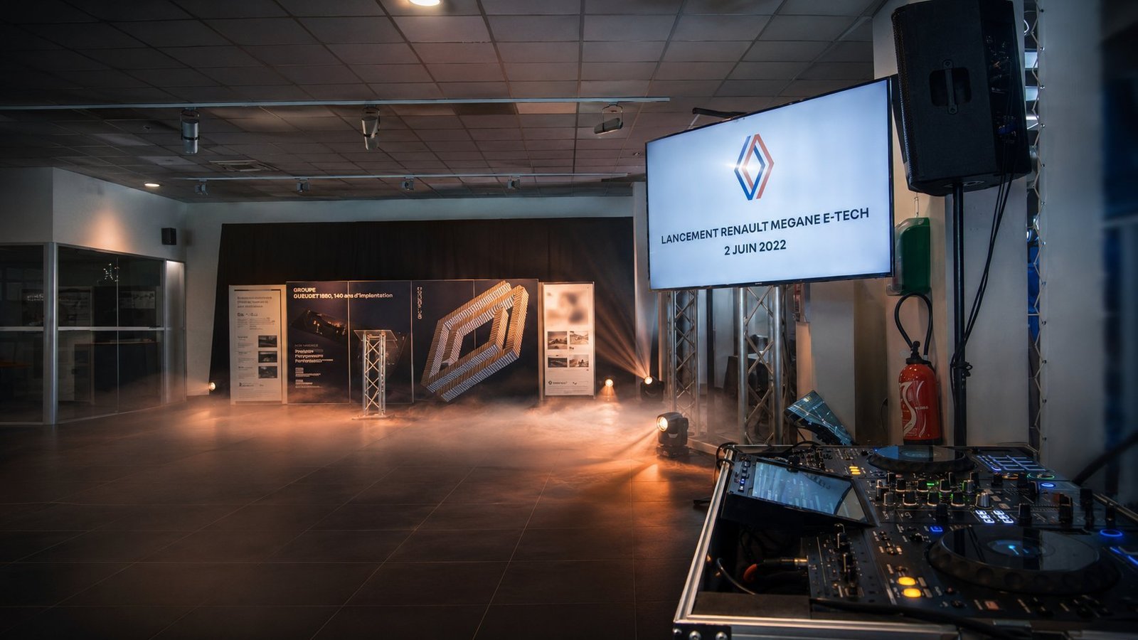 Lancement Renault Mégane E-Tech 2 juin 2022 par BLK Production, écran LCD affichant le logo Renault, structure aluminium, fumée lourde et faisceaux ambrés, régie DJ Pioneer en premier plan