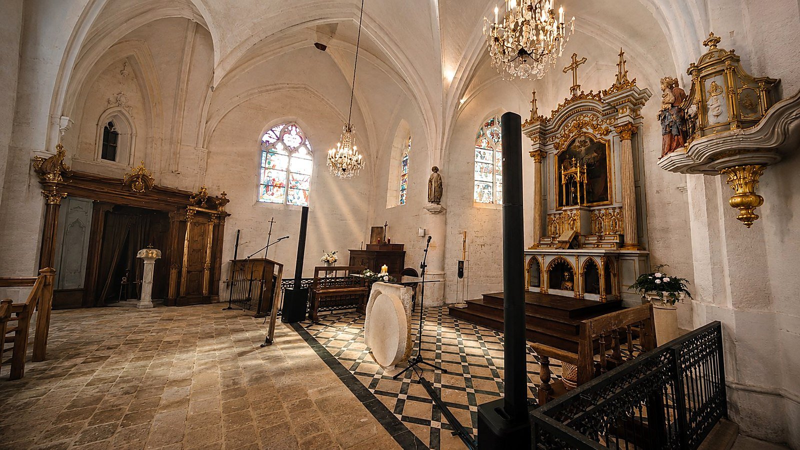 Sonorisation discrète d'une cérémonie religieuse à l'église par BLK Production, colonne de sonorisation haut de gamme noire verticale intégrée dans le décor de l'autel avec lustres et vitraux